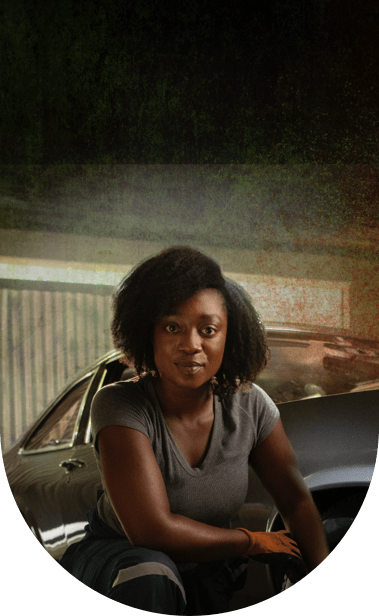 Smiling woman kneeling and fixing car tires.